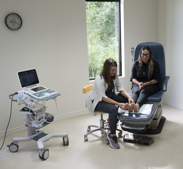 Docteure qui examine un pied, une machine échographie est visible à ses côtés
