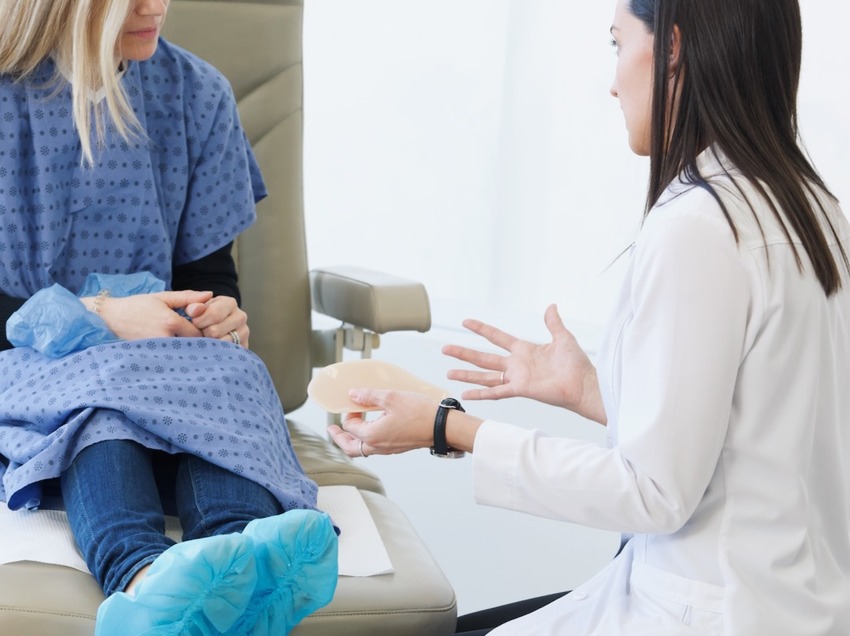 Podiatrist holding a custom orthotic and discussing with a patient
